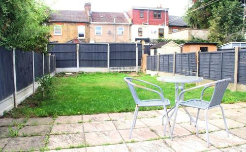 two chairs and a table in a yard with a fence at 3 bedroom house,4beds, 2 baths Ilford ,12 mins to Stratford in London