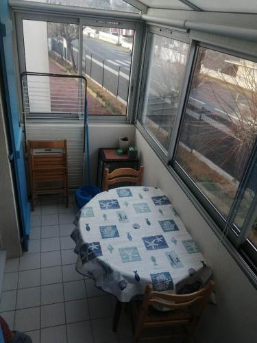 une table et des chaises dans une pièce avec des fenêtres dans l'établissement Studio La fermette d'eden 2 personnes, à Saint-Jean-de-Monts