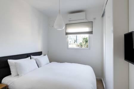 a white bedroom with a bed and a television at Peaceful Terrace by Five Stay in Tel Aviv