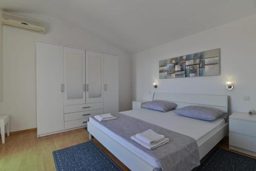 een witte slaapkamer met een bed en een witte kast bij Rina Vacation home in Trogir