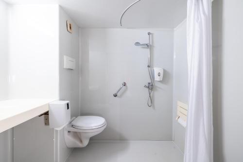 a white bathroom with a toilet and a shower at Premiere Classe Angers Beaucouzé in Beaucouzé