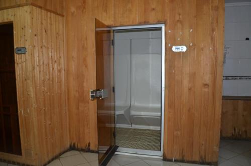una puerta de ducha de cristal en una habitación con paredes de madera en HOTEL SENATE JUJA, en Thika