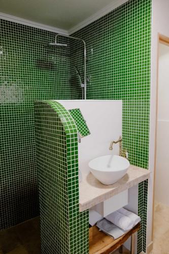 La salle de bains est pourvue de carrelage vert, d'un lavabo et d'une douche. dans l'établissement Suite de Diane - Premiere conciergerie, à Nîmes