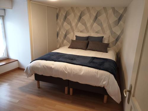 a bedroom with a large bed with a geometric headboard at Maisons cosy de village in Gurgy