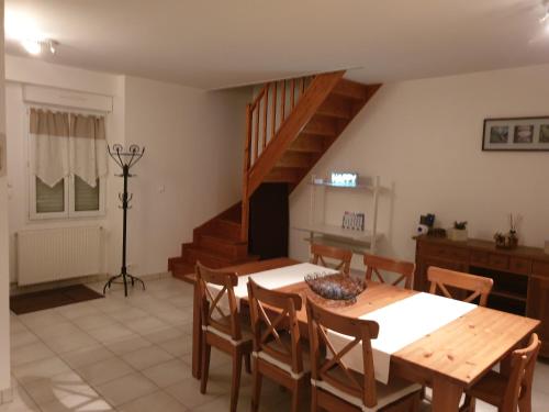 a dining room with a table and chairs and a staircase at Maisons cosy de village in Gurgy
