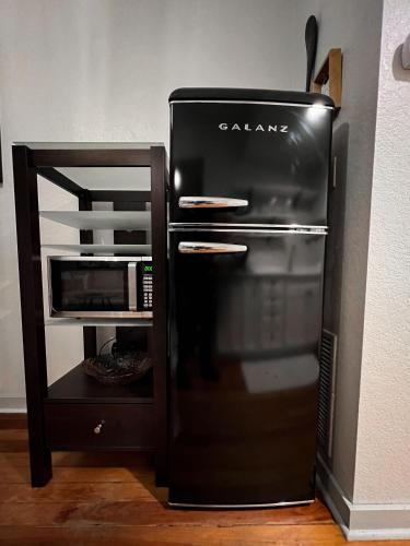 a black refrigerator in a kitchen next to a microwave at Artisan Downtown in DeLand