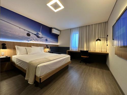 a hotel room with a large bed and a desk at Hotel Panamby Guarulhos in Guarulhos