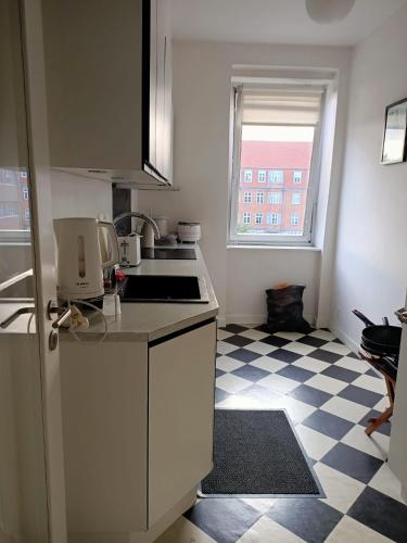 una piccola cucina con piano cottura e pavimento a scacchi di preeti singh a Copenaghen