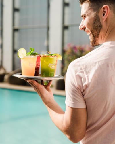 a man holding a tray with three drinks on it at The Pierside Santa Monica in Los Angeles