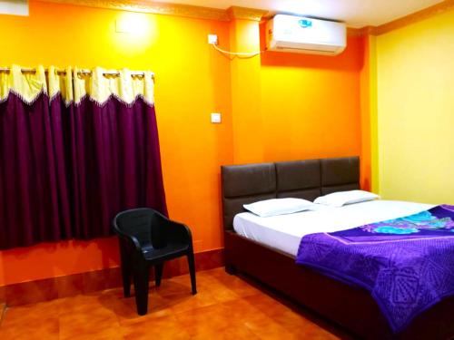 um quarto com uma cama e uma cadeira preta em Goroomgo Sahoo Palace Puri Near Sea Beach em Puri