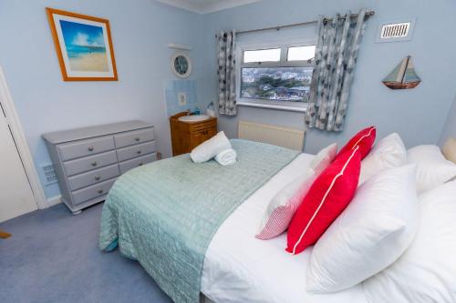a bedroom with a bed with red pillows on it at Tylecroft in Noss Mayo