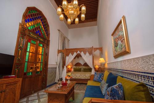 een woonkamer met een bed en een kroonluchter bij Riad Myra in Fès