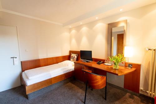 a bedroom with a bed and a desk with a computer at Hotel Carlton Munich in Munich