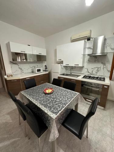 una cocina con mesa y sillas y una cocina con armarios blancos. en Appartamento Annesca - Delta del Po, en Porto Tolle