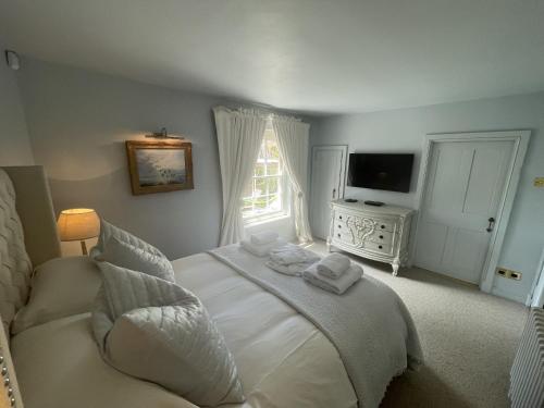 1 dormitorio con cama blanca y ventana en Luxury Cottage, close to Quay. Pretty Courtyard., en Blakeney