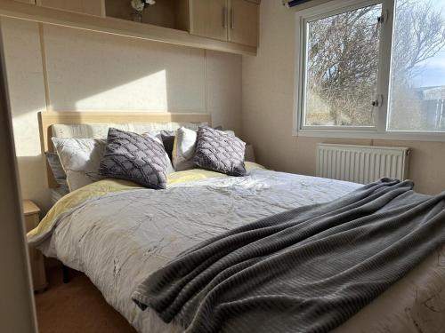 a bedroom with a bed with pillows and a window at Captivating 2-Bed static caravan in Holyhead in Llanfachraeth