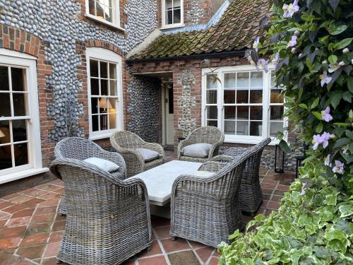 un grupo de sillas de mimbre y una mesa en un patio en Luxury Cottage, close to Quay. Pretty Courtyard., en Blakeney