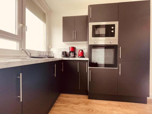 une cuisine avec des armoires noires et un four micro-ondes dans l'établissement Spacieux logement en famille - 296, à Sotteville-lès-Rouen