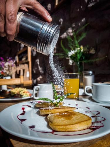 a person is sprinkling syrup on a plate of food at El Balcón in Cusco
