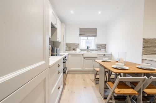 eine Küche mit weißen Schränken und einem Holztisch in der Unterkunft Steels cross House in Lanark