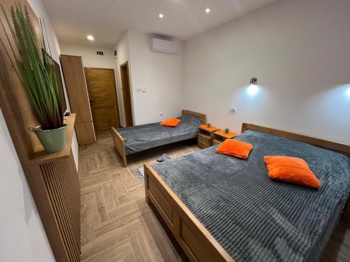 sypialnia z 2 łóżkami i pomarańczowymi poduszkami w obiekcie Apartmani Ristanović Užice w mieście Užice