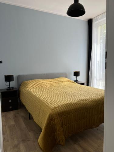 a bedroom with a bed with a yellow bedspread at Aquarius Kilińskiego 2 in Grodzisk Mazowiecki