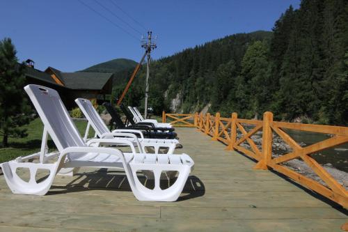 a row of white chairs sitting on a wooden deck at Forest House in Tatariv