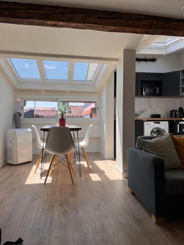 un salon avec une table et des chaises et une cuisine dans l'établissement Charmant T2 au coeur de Toulouse quartier Carmes/Esquirol, à Toulouse