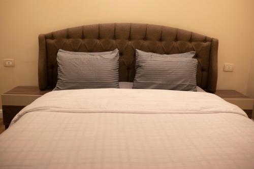 a large bed with two pillows and a large headboard at Munir’s residence in Cairo