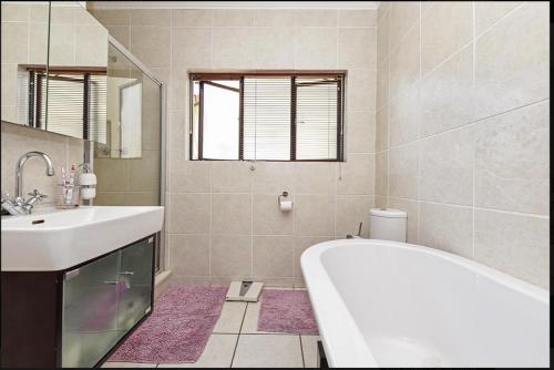 y baño con bañera, lavabo y espejo. en The Kanyin, en Sandton