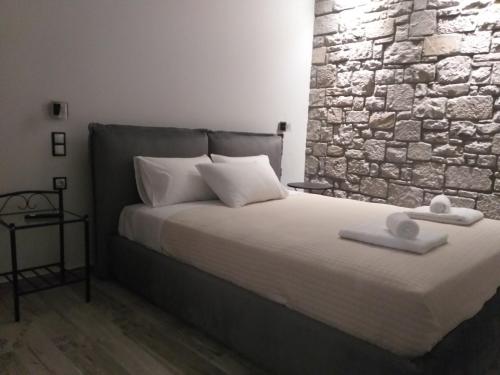 a bedroom with a bed with a stone wall at Villa la Vago in Agios Ioannis Kaspaka