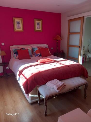 une chambre avec un grand lit aux murs rouges dans l'établissement AU DOMAINE DE SOPHIE Chambres d'hôtes Crasville Manche, à Crasville