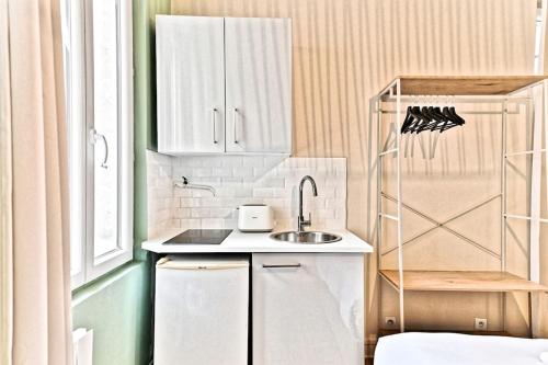 une petite cuisine avec des armoires blanches et un évier dans l'établissement Studio au centre de Paris - 14ème arrondissement, à Paris