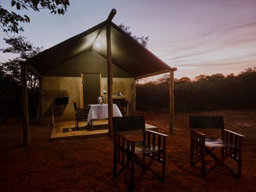 a tent with a table and chairs in a field at Mountain Peak Game Lodge and Camping in Outjo