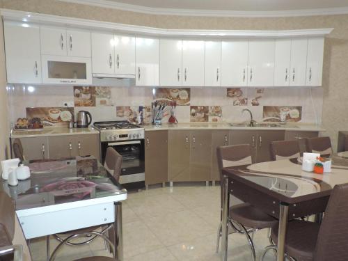 a kitchen with white cabinets and a table with chairs at Hotel Lotus in Akhaltsikhe