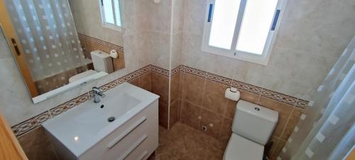 La salle de bains est pourvue d'un lavabo, de toilettes et d'un miroir. dans l'établissement Baix Maestrat Apartamento en 1ª línea de playa, à Peñíscola