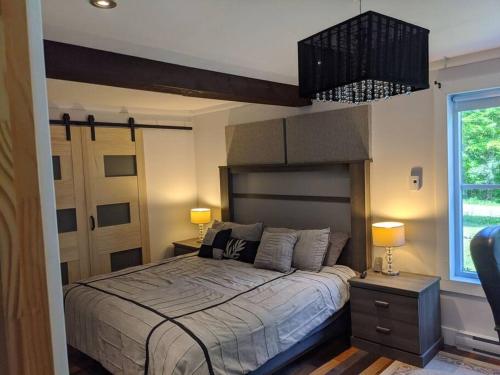 a bedroom with a large bed and a chandelier at Chalet lacbrome in Lac-Brome