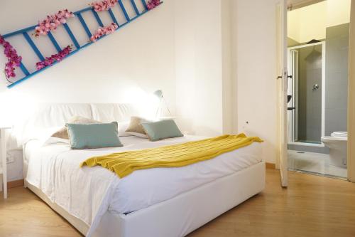 a bedroom with a white bed with a yellow blanket on it at B&S Suite Colosseo in Rome
