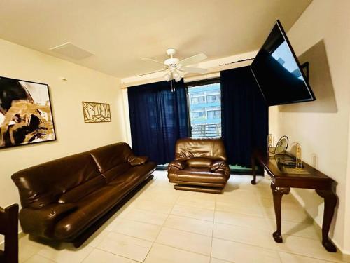 uma sala de estar com um sofá de couro e uma televisão em 3BR Apartment in Acacias San Ignacio em Tegucigalpa