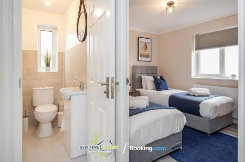 a bedroom with two beds and a toilet and a sink at 5 Bed House By Sentinel Living Short Lets & Serviced Accommodation Windsor Ascot Maidenhead With Free WiFi & Garden in White Waltham