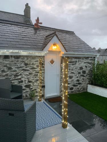 a house with a white door with lights on it at White Mermaid Cottage Anglesey Holidays in Newborough