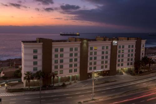安托法加斯塔的住宿－安託法加斯塔NH酒店，一座以大海为背景的街道上的建筑