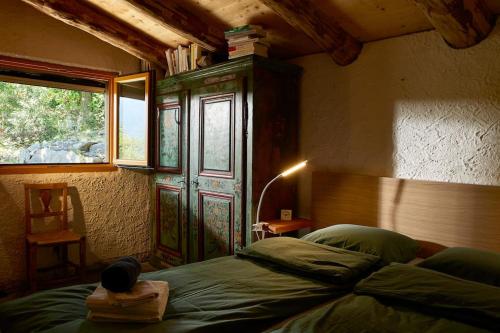 a bedroom with a bed with a wooden headboard and a window at Wild Valley Rustico Style in Valle Onsernone in Auressio
