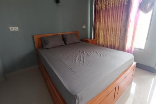 Schlafzimmer mit einem Bett mit einem Holzrahmen und einem Fenster in der Unterkunft OYO 93603 Nurbata Holdings in Kuta Lombok