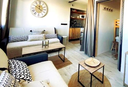 a living room with a couch and a clock on the wall at Coeur de station ESF - Pied de pistes Baïkonour in Le Corbier