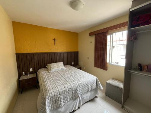- une chambre avec un lit et une croix sur le mur dans l'établissement Apartamento em Icaraí - 2 suítes, à Caucaia