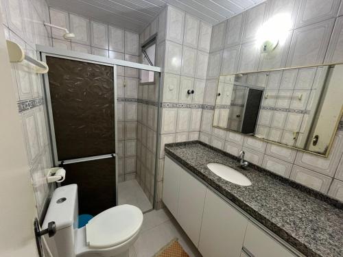 a bathroom with a toilet and a sink and a mirror at Apartamento no Icaraí - 2 suítes in Caucaia