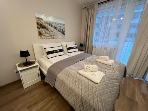a bedroom with a bed with two towels on it at Apartamenty Kapitańskie Bliżej Morza in Kołobrzeg