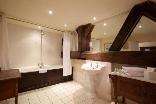 uma casa de banho com uma banheira e um lavatório e uma banheira em Risley Hall Hotel em Risley