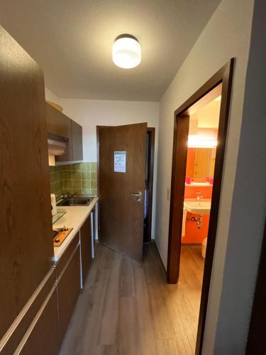 - une cuisine avec un évier et une porte menant à une chambre dans l'établissement Appartement mit Bademantelgang zur Wohlfühltherme, à Bad Griesbach im Rottal